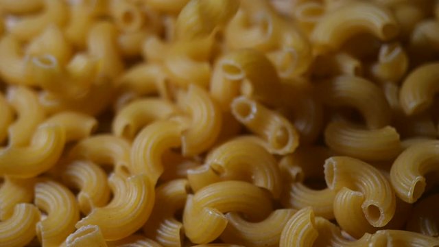 Raw macaroni falling in slow motion. Close-up elbow macaroni. Italian cuisine concept.