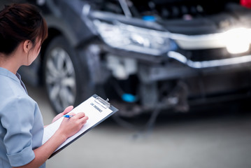 Insurance agent staff writes on clipboard while checking the car after being evaluated and...