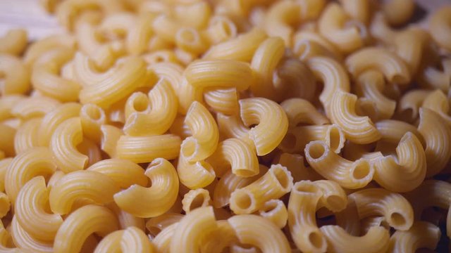 Raw macaroni rotation. Close-up elbow macaroni. Italian cuisine concept. 4K