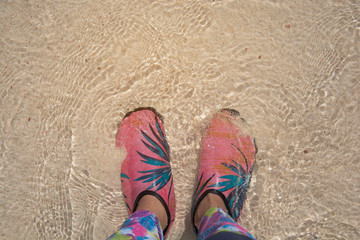 Wading shoes of woman standing on the beach sand, beach of Krabi , Thailand