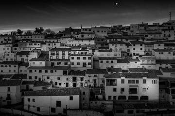 Black and white image of colorful houses with square windows and traditional roofs in Alcala del Jucar Spain