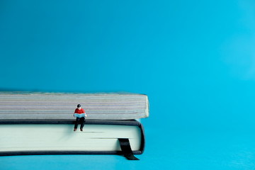 Young man sitting on book pile while reading