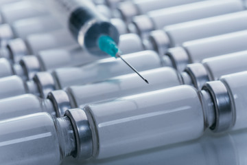 Medicine, Injection, vaccine and disposable syringe, drug concept. Sterile vial medical syringe needle. Macro close up. Glass medical ampoule vial for injection. Bottles ampule with aluminum cap.