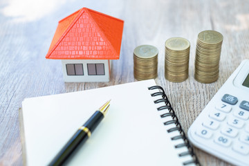 A coin in a hemp bag placed near Orange roof house Money saving ideas for buying a home or loan for...