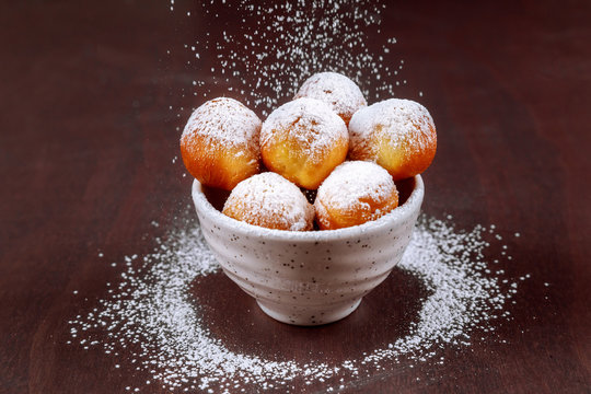 Sprinkle homemade munchkins with sugar powder on blue dish.