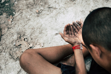 poor child or beggar begging you for help sitting at dirty slum. concept for poverty or hunger...
