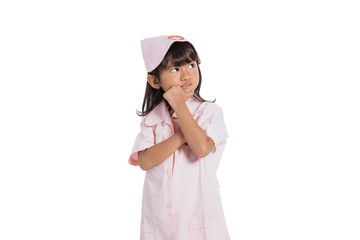 Asian little girl wearing a nurse uniform with one hand holding her chin on white background