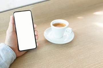 Fototapeta na wymiar Mockup image blank white screen cell phone.man hand holding texting using mobile on desk at coffee shop.background empty space for advertise text.people contact marketing business,technology 