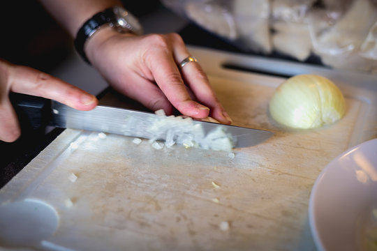 woman cuts onions on a white plastic board