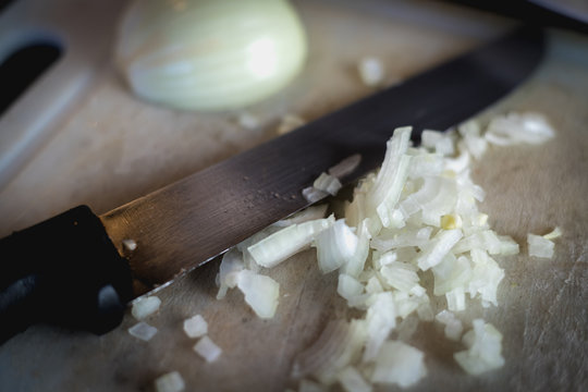 woman cuts onions on a white plastic board