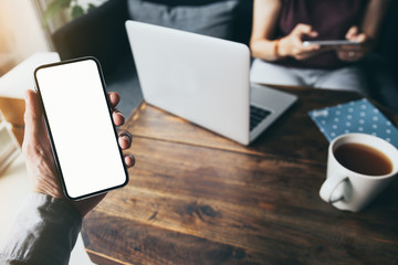 Mockup image blank white screen cell phone.man hand holding texting using mobile on desk at coffee...