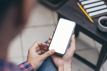 Mockup image blank white screen cell phone.man hand holding texting using mobile on desk at coffee shop.background empty space for advertise text.people contact marketing business,technology 