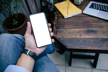 Mockup image blank white screen cell phone.man hand holding texting using mobile on desk at coffee shop.background empty space for advertise text.people contact marketing business,technology 