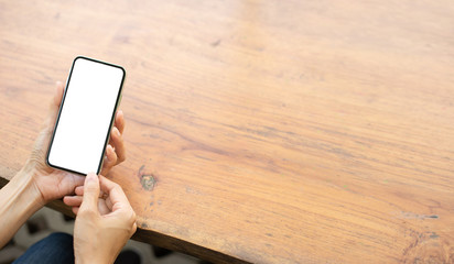 Mockup image blank white screen cell phone.man hand holding texting using mobile on desk at coffee shop.background empty space for advertise text.people contact marketing business,technology 