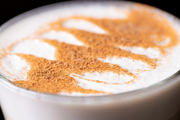 A very close view of the top foam and latte art of a Chai Latte against a dark background