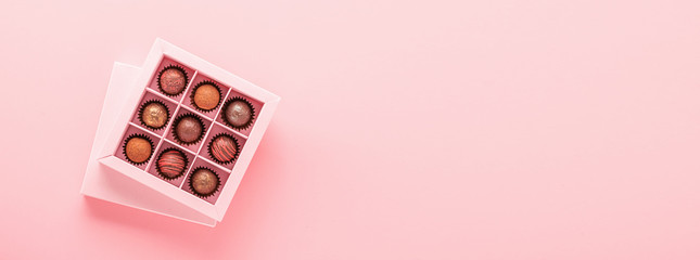 Handmade chocolates truffle in a craft box on a pink background. Gifts festive food love concept....