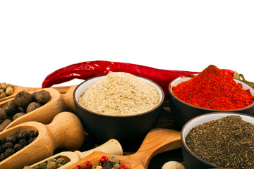 Different peppers in a ceramic cups, wooden scoops and red hot chili pepper on white background. 
