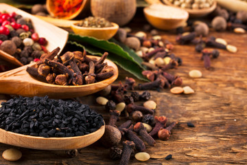 Different spices in spoons on a wooden background.