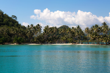 Tropical island sand beach on the sea. Blue sky with clouds.