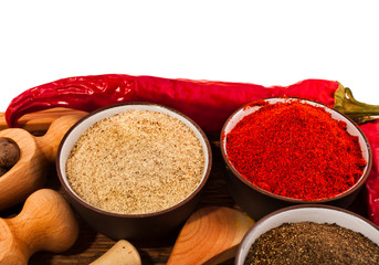 Different peppers in a ceramic cups and red hot chili pepper on wooden background. 