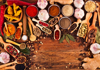 Obraz na płótnie Canvas Spices on wooden background. Different pepper powder, peppercorns, ginger, red hot chili pepper, turmeric, saffron, cardamon, sea salt, coriander, bay leaf, cloves. 