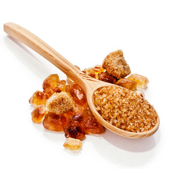 Brown sugar crystals and brown sugar in a wooden spoon isolated on white background.