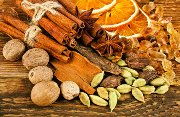 Slices of dried orange, brown sugar crystals, cardamom, nutmeg, cinnamon sticks and star anise on wooden background. Sweet spices. Top view. 