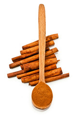 Cinnamon sticks and powder of cinnamon in a wooden spoon isolated on white background. Top view.