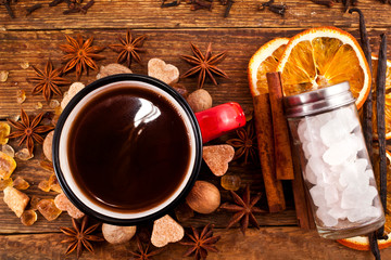 Coffee in an enamel cup with crystals of sugar, star anise, vanilla pods, cinnamon sticks, nutmeg...