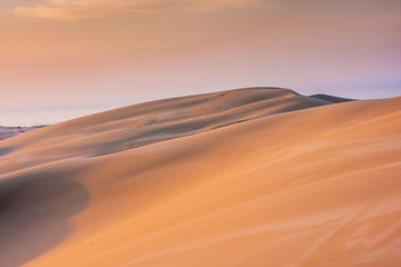 Fototapeta na wymiar A big bright orange sand dune. Stockton Sand Dunes near the coast, Worimi Regional Park, Anna Bay, Australia
