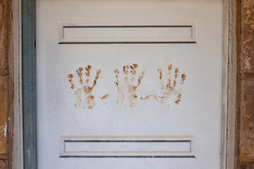 Painted white wooden door with handprints in the middle made of orange clay.