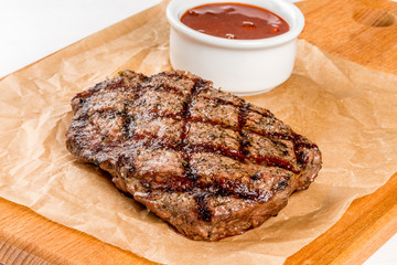 Beef steak on a wooden board with sauce