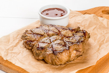 Grilled pork steak with sauce on a wooden board