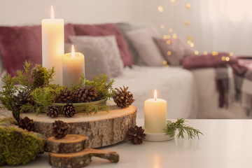 Composition of candles on  white table against the background of sofa at home