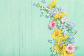 frame of beautiful flowers on green wooden background