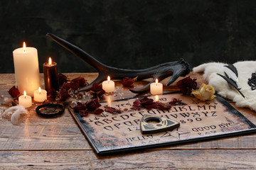 Mystic ritual with Ouija and candles. Devil's board concept, black magic or fortune telling rite...
