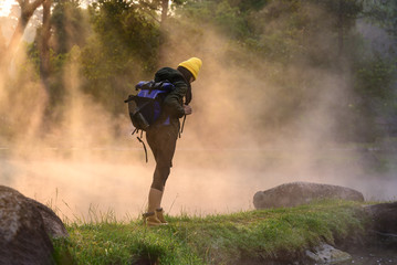 Obraz premium woman trekking alone on the lake of forest mountain with hot spring water flowing the lake in the morning, cheerfully on the move freshly morning