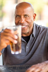 Mature African American man drinking at a restaurant.