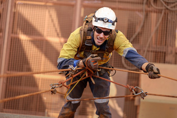 Happy industry rope access miner working at height performing rope transferring using descender...