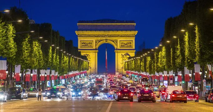 View down the Champs Elysees to the Arc de Triomphe, illuminated at dusk, Paris, France - Time lapse