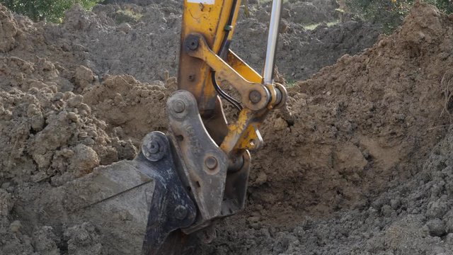 Close-up of an excavator scoop as it removes dirt and mud from a blocked road.