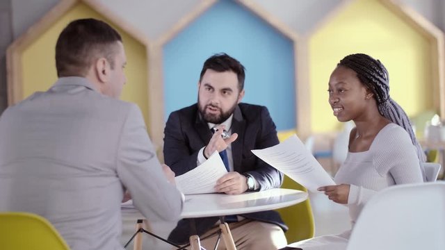 Young african american business woman at the negotiating table explains to two businessmen her position and views on the upcoming deal.