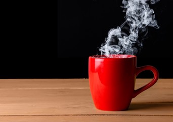A red hot cup of coffee on a wooden desk