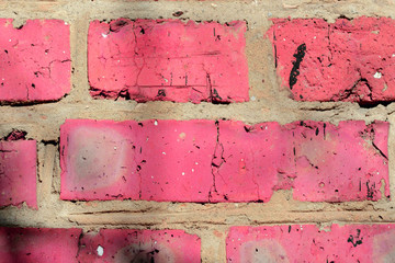 Fragment of an old brick wall painted pink paint with a shadow from tree branches on a sunny day. Abstract background