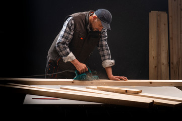 Carpenter works with electrical planer