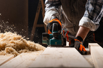 Carpenter works with electrical planer