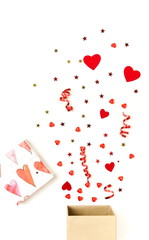 Valentine's day background.  gift box with various party confetti, red hearts and decoration isolated on white background top view. 