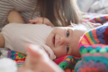 Close-up portrait of cute little infant girl lying on bed in morning light