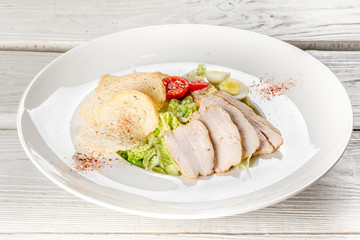 Caesar and chicken salad on a white plate