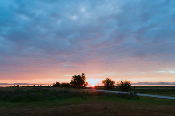 sunset in the park near the river. Field and bench in the foreground, the silhouette of trees and mountains in the background